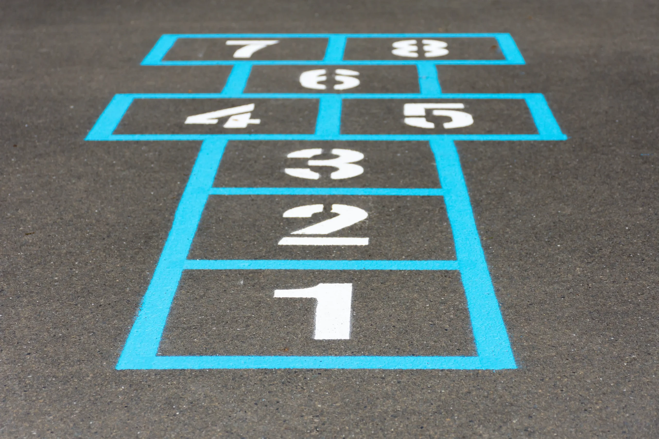 Playground markings installation crew laying a thermoplastic grid design in Redhill